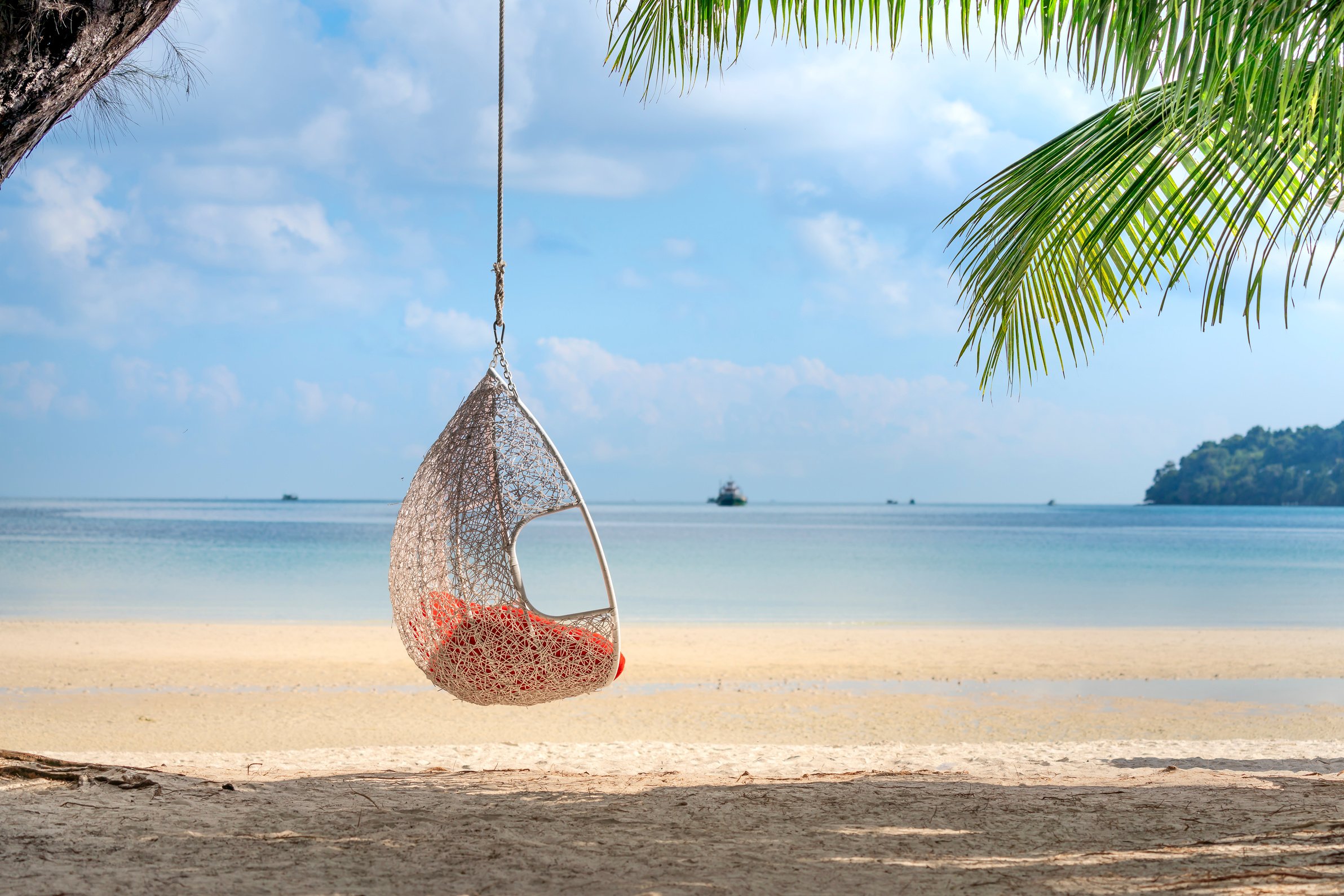 Wicker hanging egg chair on picturesque seaside